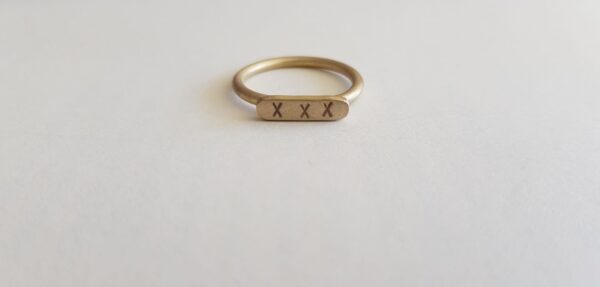 Brass round wire signet ring with letter punch kisses front view