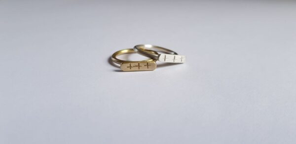 Front angle of silver and brass crisscross signet ring duo