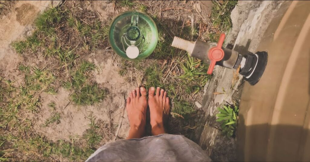Barefoot and happy on the farm fetching water from the rain tank