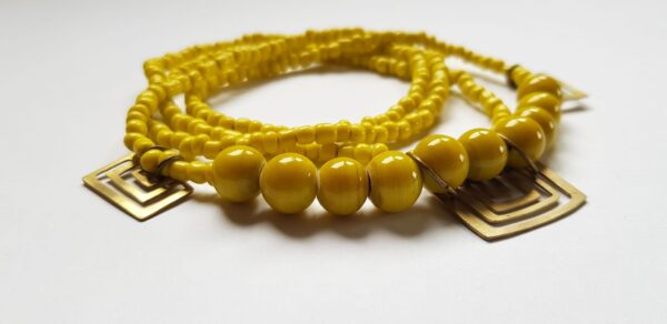 Yellow glass bead necklace with brass handmade brass cutouts close up