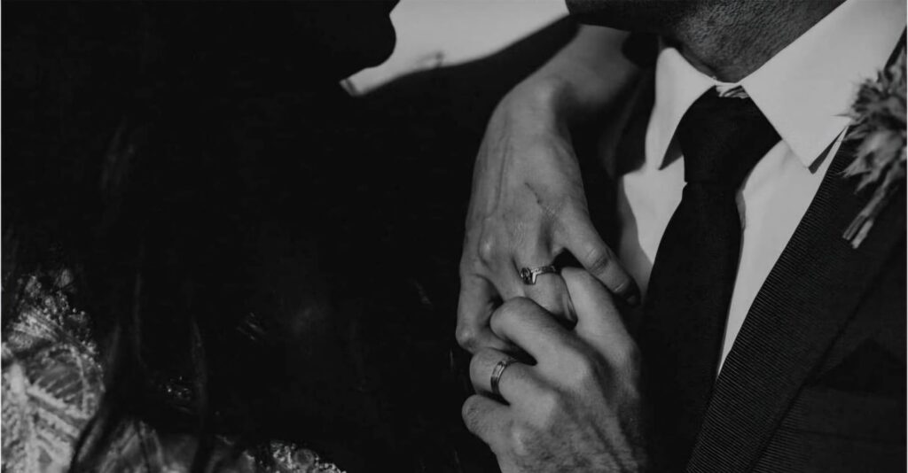 Bride and groom holding hands with their wedding rings visible