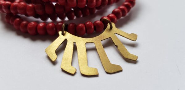 Close-up of red dyed wood bead necklace with brass kids drawing from Malawi