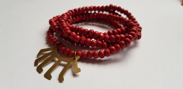 Left angle of red dyed wood bead necklace with brass Malawi kids drawn symbol
